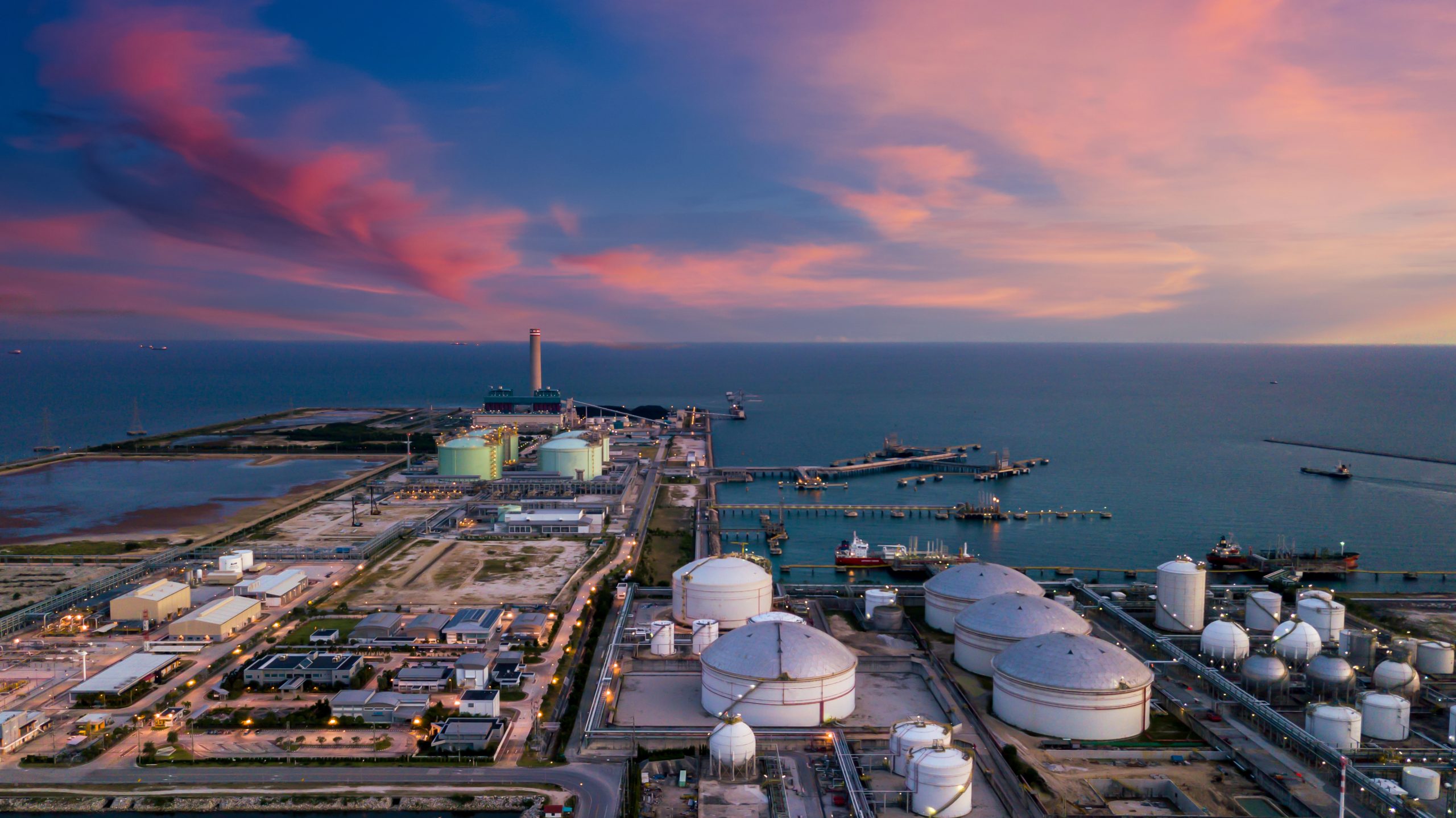 Aerial view oil terminal and coal power plant station in sea, White oil storage tank chemical petroleum petrochemical refinery product, Tanker ship at deep ocean seaport terminal.